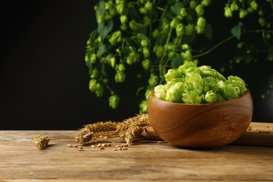 Photo of Fresh green hops, wheat grains and spikes on wooden table, space for text