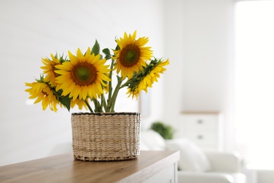 Beautiful yellow sunflowers on wooden table in room, space for text