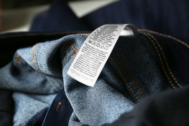 Clothing label with care instructions and content information on denim garment, closeup