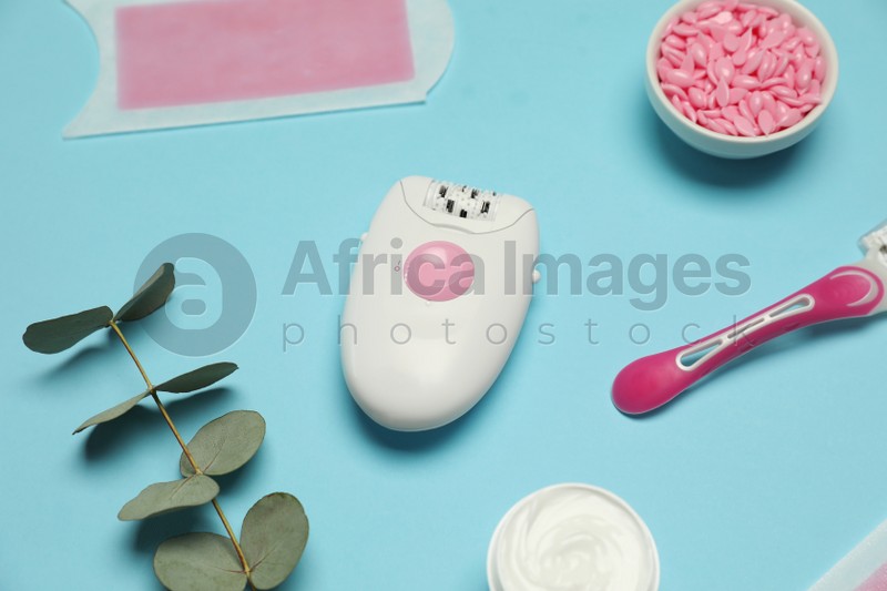 Epilator and other hair removal products on light blue background