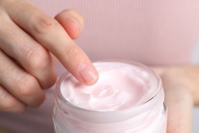 Woman holding jar of hand cream, closeup. Space for text