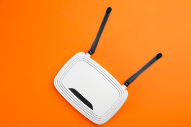 Modern Wi-Fi router on orange background, top view