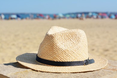 Stylish straw hat on stone surface near sea