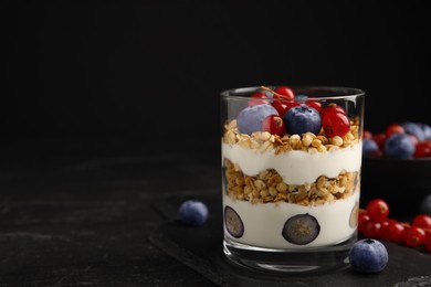 Delicious yogurt parfait with fresh berries on black table, space for text