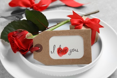 Beautiful place setting with gift box and flower on table, closeup. Valentine's day romantic dinner