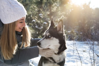 Young woman with dog in forest on winter day, space for text