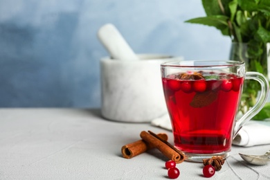 Tasty hot cranberry tea with mint and fresh ingredients on light table. Space for text