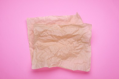 Sheets of crumpled baking paper on pink background, top view