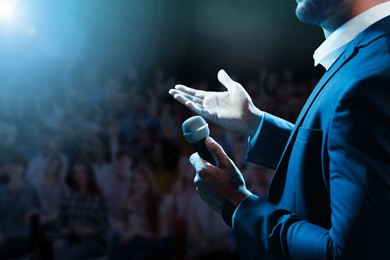 Motivational speaker with microphone performing on stage, closeup