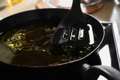 Frying pan with used cooking oil and spatula on stove, closeup