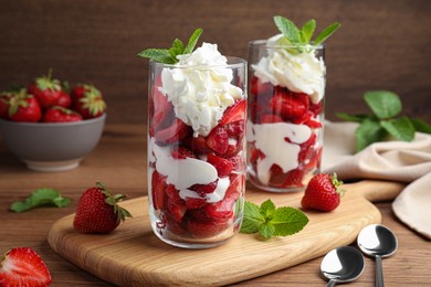 Delicious strawberries with whipped cream served on wooden table