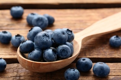 Spoon with tasty fresh blueberries on wooden table, closeup