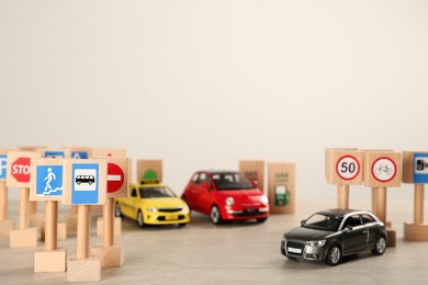 Many different miniature road signs and cars on wooden table, space for text. Driving school