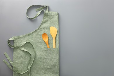 Photo of Clean apron with wooden kitchen tools on light grey background, top view. Space for text