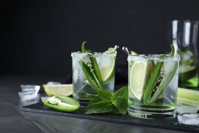 Photo of Spicy cocktail with jalapeno, cucumber and lime on black table. Space for text