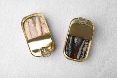 Photo of Open tin cans with mackerel fillets on grey table, flat lay