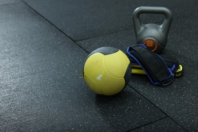 Yellow medicine ball, kettlebell and weighting agents on floor, space for text