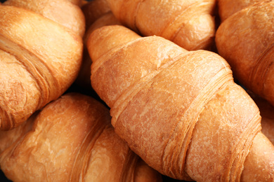 Tasty fresh croissants as background, closeup view