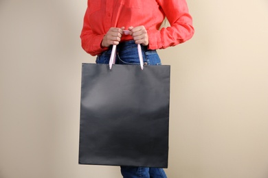 Woman holding paper shopping bag on color background. Mock up for design