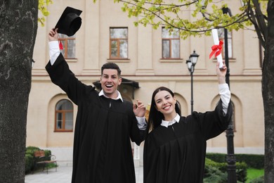 Happy students with diplomas after graduation ceremony outdoors