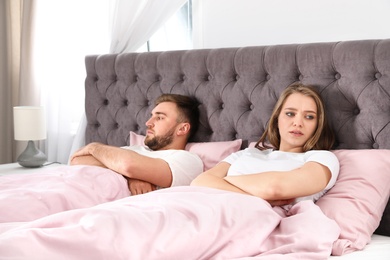 Photo of Young couple with relationship problems in bed at home