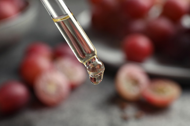 Dropper with natural grape seed oil on blurred background, closeup. Organic cosmetic