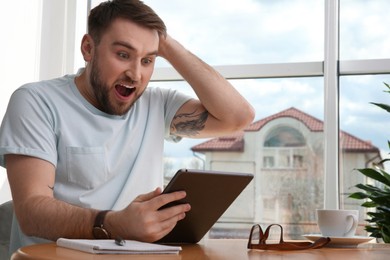 Emotional man participating in online auction using tablet at home