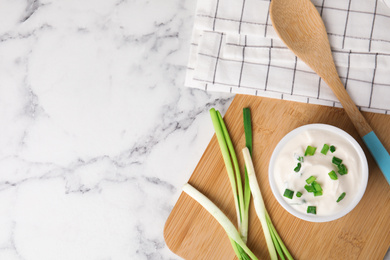Fresh sour cream with onion on white marble table, flat lay. Space for text