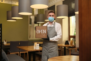 Waiter with OPEN sign in restaurant. Catering service during coronavirus quarantine