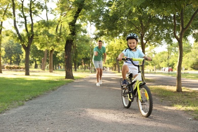 Happy father teaching his son to ride bicycle in park
