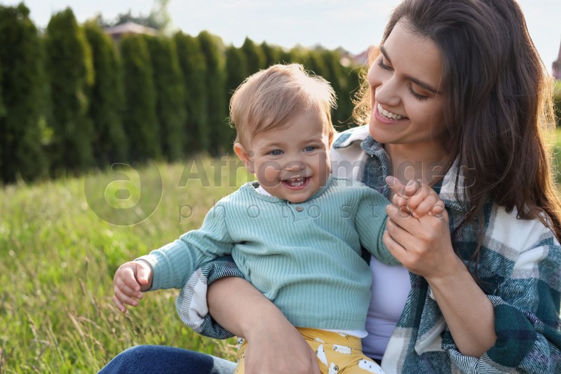 Photo of Happy mother with her cute baby at backyard on sunny day, space for text