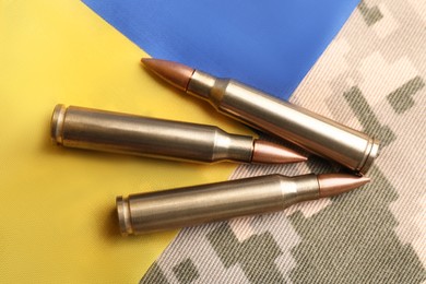 Bullets and Ukrainian flag on military camouflage, flat lay