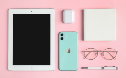 MYKOLAIV, UKRAINE - JULY 10, 2020: Flat lay composition with Iphone 11, IPad tablet and AirPods on pink background