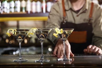 Barman serving glasses of lemon drop martini on counter, closeup. Space for text