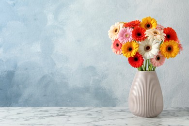 Bouquet of beautiful colorful gerbera flowers in vase on white marble table against light blue background. Space for text