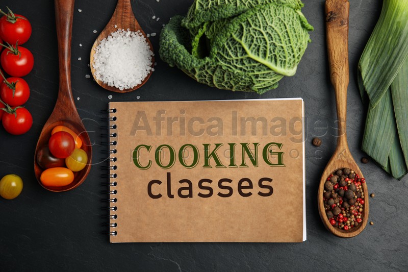 Notebook with inscription Cooking Classes and different ingredients on black table, flat lay