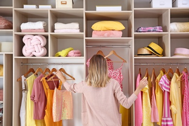 Woman choosing clothes from large wardrobe closet