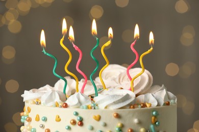 Beautiful birthday cake with burning candles on blurred background, closeup