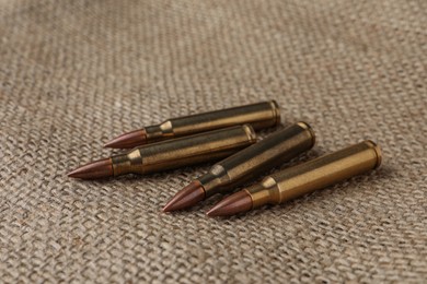 Photo of Many brass bullets on burlap, closeup. Firearm ammunition