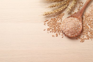 Wheat bran, kernels and spikelets on wooden table, flat lay. Space for text