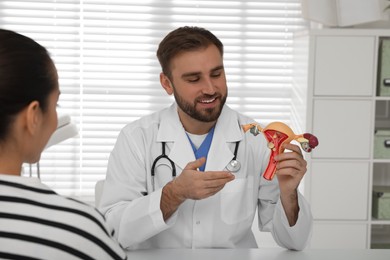 Gynecologist demonstrating model of female reproductive system to young woman in clinic
