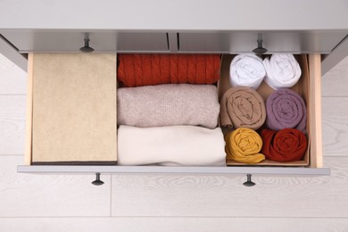 Open drawer with folded clothes indoors, top view. Vertical storage