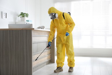 Employee in protective suit sanitizing office. Medical disinfection