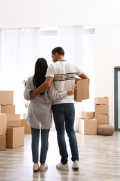 Couple in room with cardboard boxes on moving day