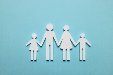 Photo of Paper family figures on light blue background, top view. Insurance concept