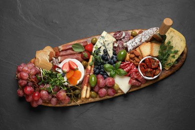 Set of different delicious appetizers served on black table, top view