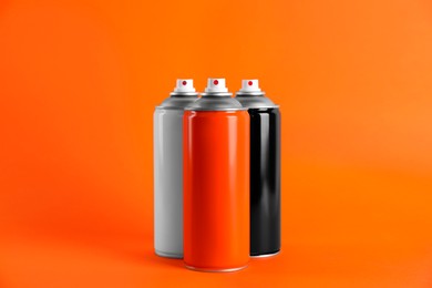 Colorful cans of spray paints on orange background
