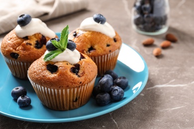 Photo of Plate of tasty muffins and blueberries on marble table