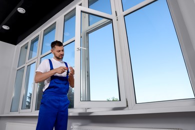 Construction worker adjusting installed window with screwdriver indoors