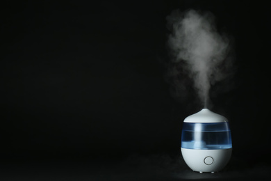 Modern air humidifier on black background. Space for text